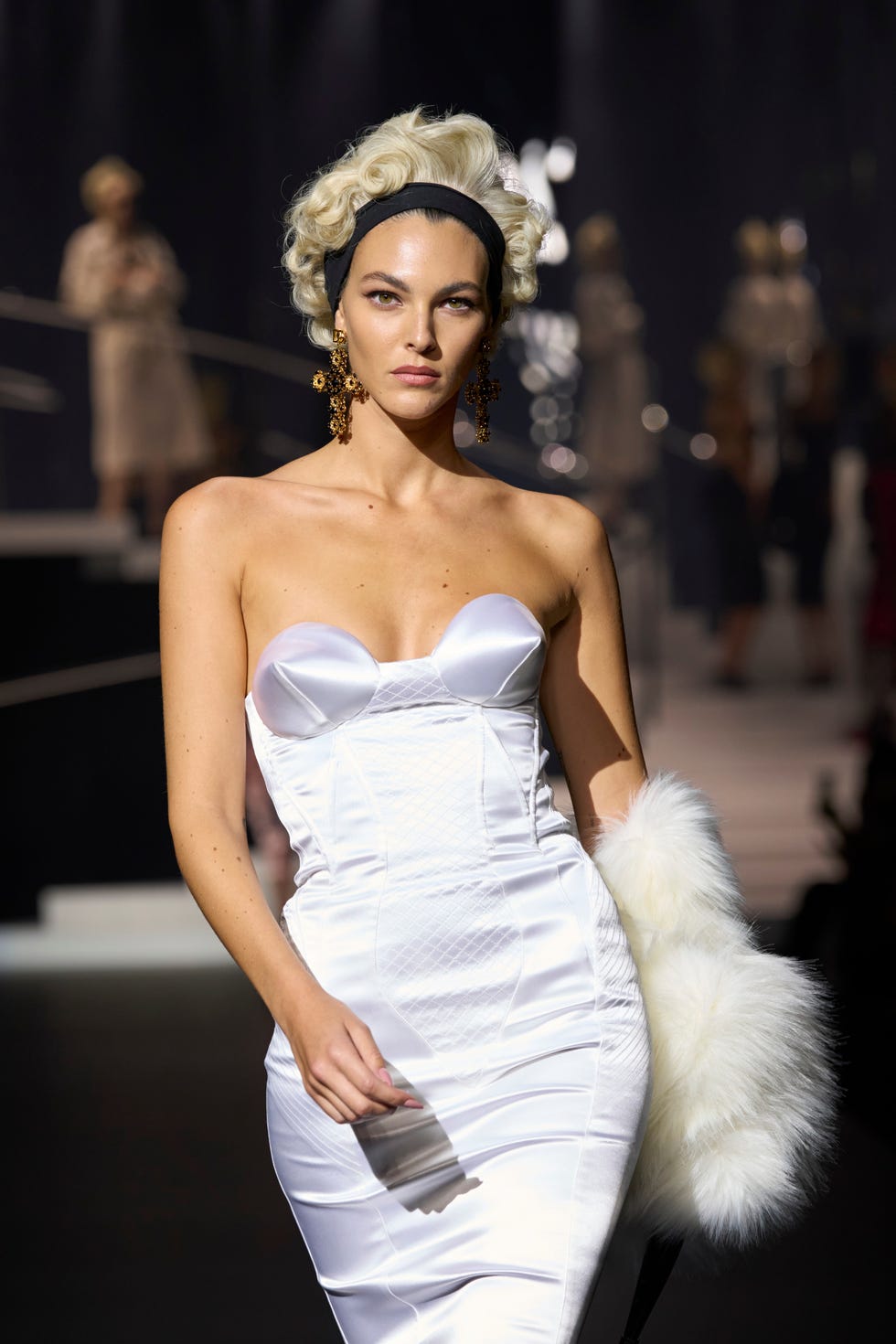 model wearing a white strapless gown on a fashion runway