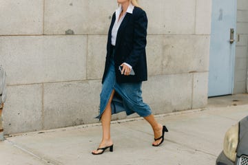 a man in a black jacket and blue jeans walking on a sidewalk