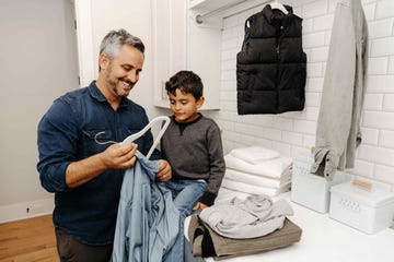 a man and a child are reviewing clothing items in a laundry room