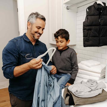 a man and a child are reviewing clothing items in a laundry room a man and a child are reviewing clothing items in a laundry room