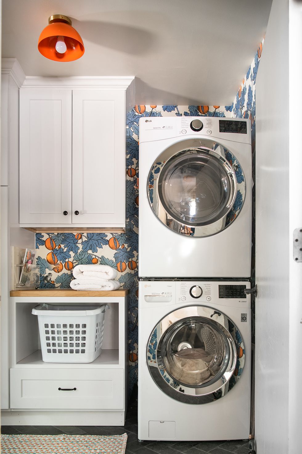 a washing machine in a room with vibrant wallpaper and laundry basket storage