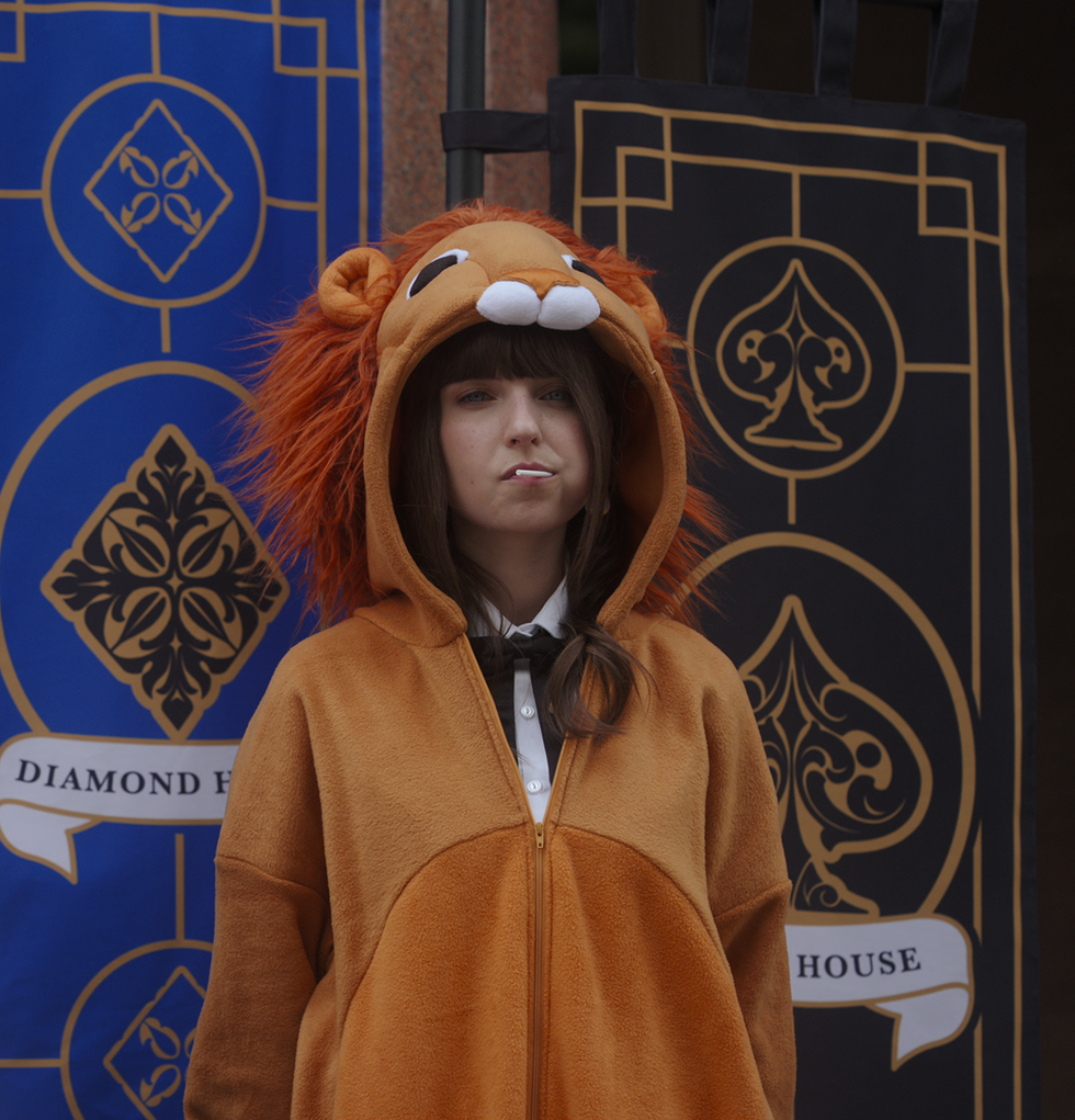 person wearing a lion costume hoodie in front of decorative banners