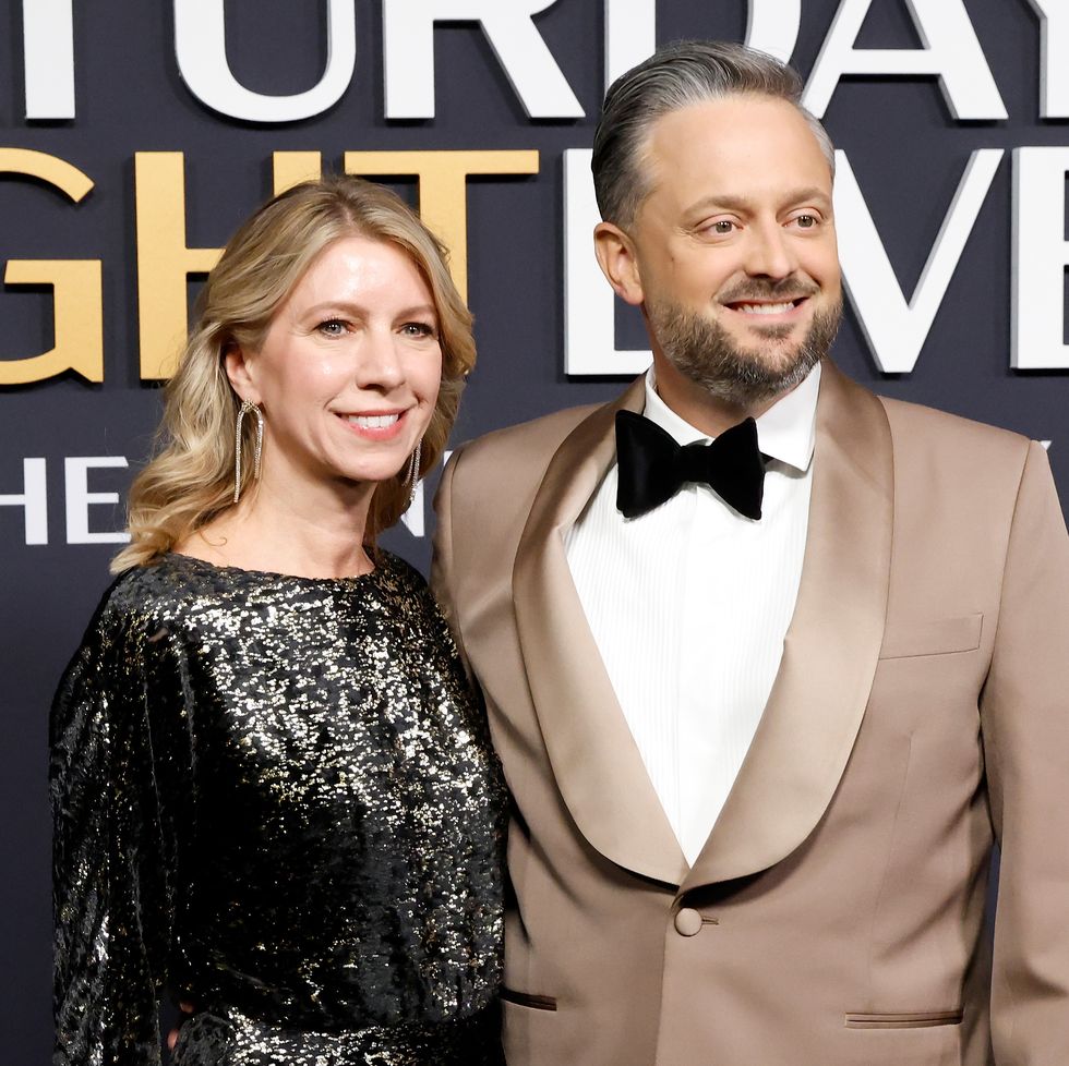 a woman and a man embrace while smiling for photos and looking to the right