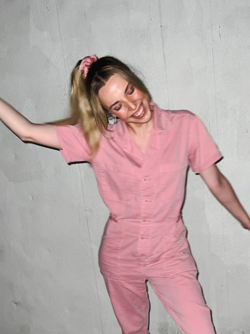 a woman wearing the pink pistola denim grover jumpsuit and laughing