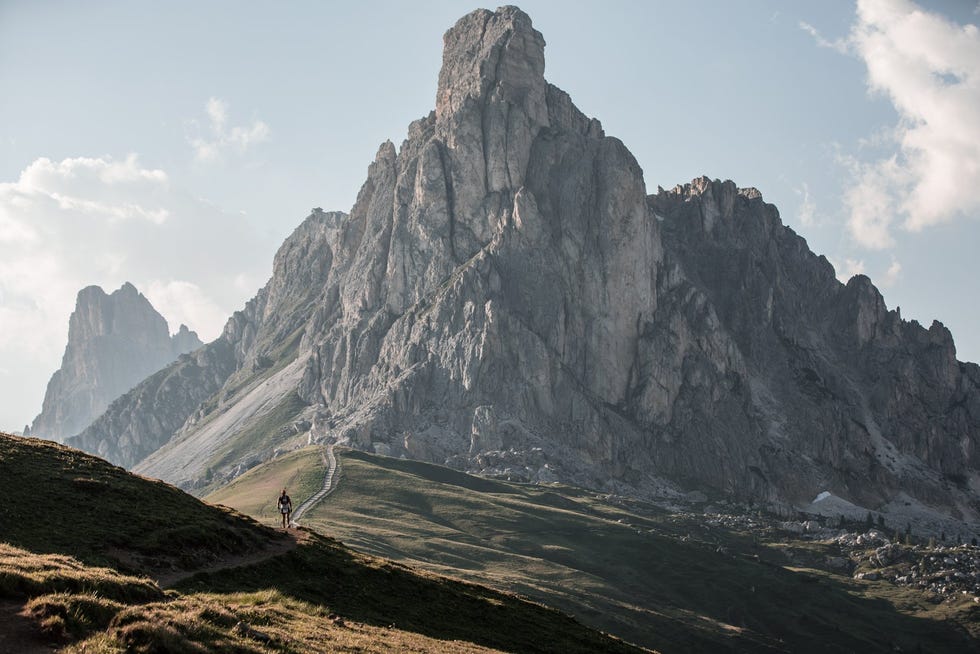 a person walking on a path between mountains