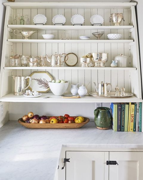 white counter top with open shelving filled with collected silver and ceramic peices