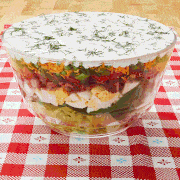 layered salad in glass bowl on picnic blanket