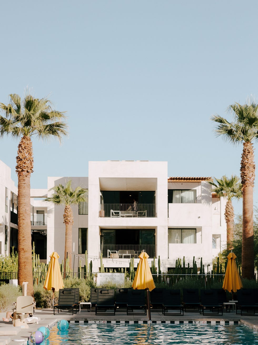 un hôtel avec une piscine devant et des parasols jaunes