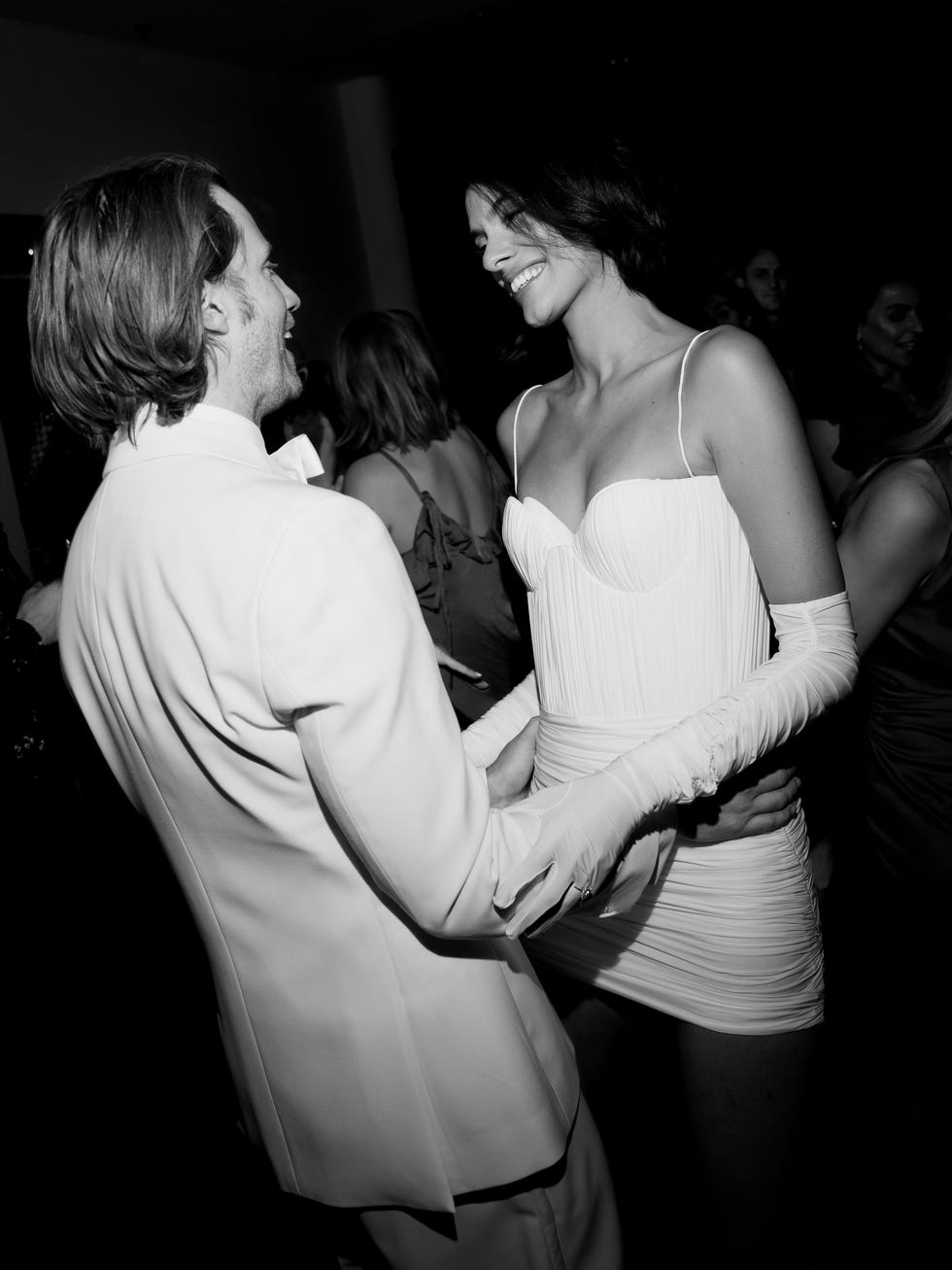 un homme en costume blanc et une femme en mini-robe blanche s'embrassent