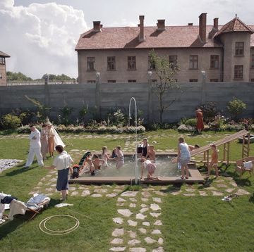 a group of people playing in a yard with chairs and tables