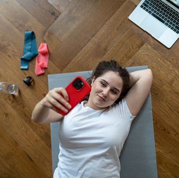 lazy girl lies on sport mat with phone and takes selfieno motivation to make exercise alone