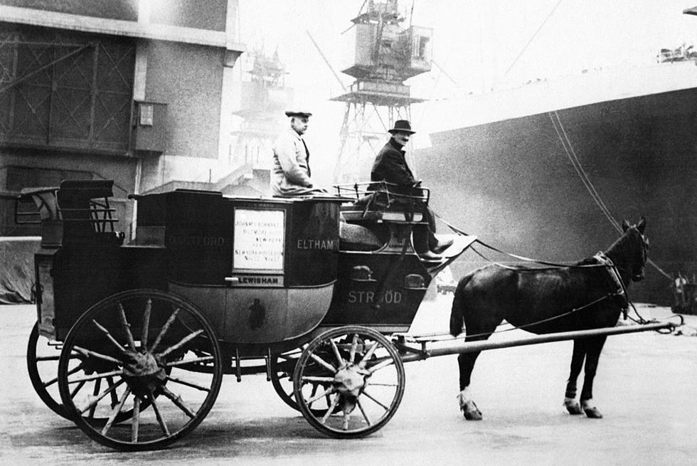 two men sit on a stagecoach carriage attached to a horse