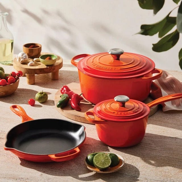 set of vibrant orange cookware with accompanying fresh ingredients and condiments