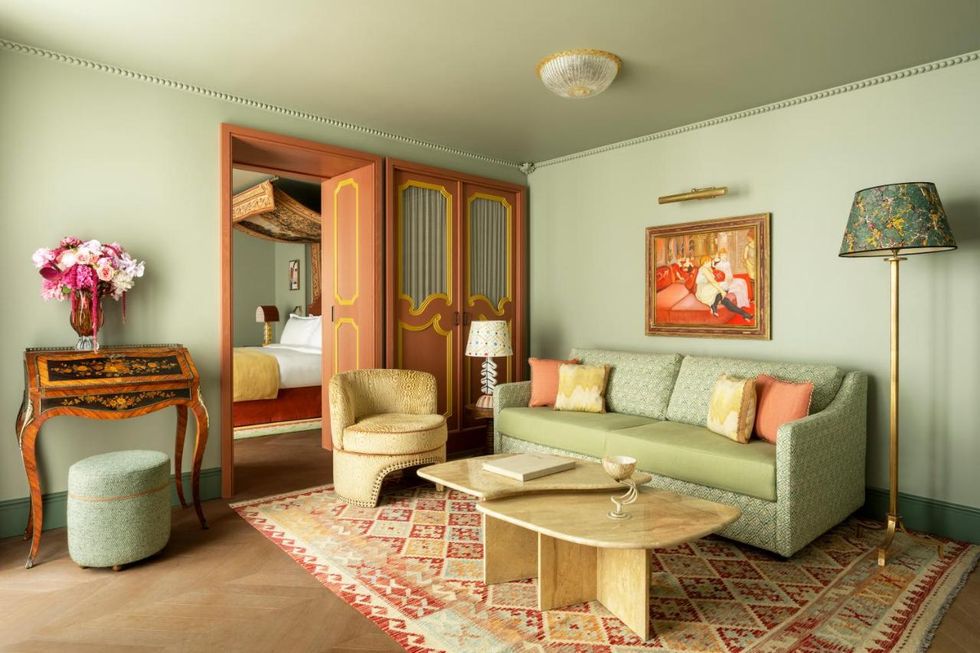 le grand mazarin view of hotel room feauting a light green sofa vintage wood and carpet