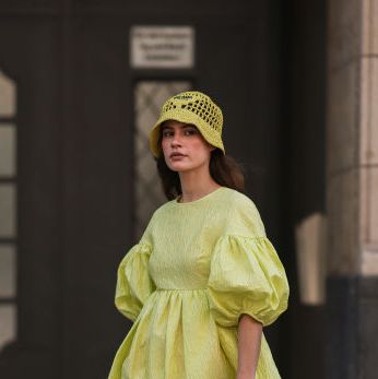 a woman carrying a prada crochet tote bag with a yellow dress and clogs on the street in berlin in a roundup of the best crochet tote bags