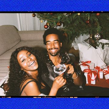 a man and woman sitting on a couch with a christmas tree behind them