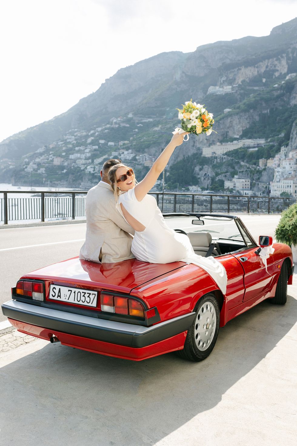 a man and woman in a convertible car with flowers on the hood