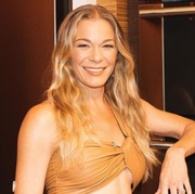 leann rimes posed in cropped orange shirt and matching high rise pants