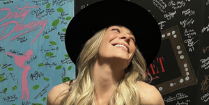 leann rimes poses backstage in a black cut out dress and wide brim hat