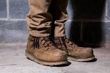 work boots on a person standing against a concrete wall