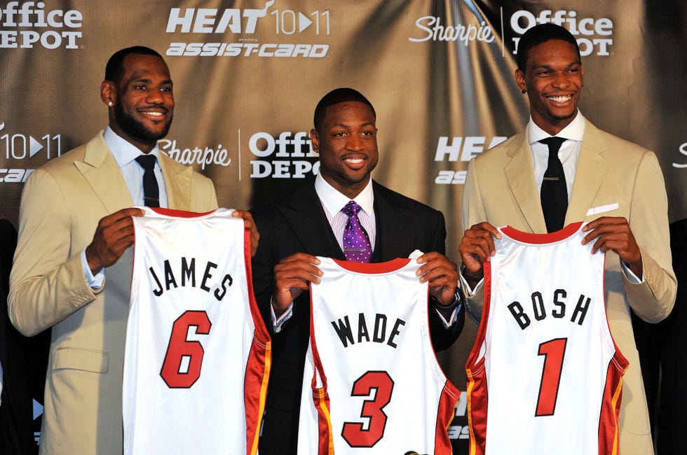 lebron james, chris bosh and dwyane wade smile and pose for photos while each holding a personalized jersey with their last name on it