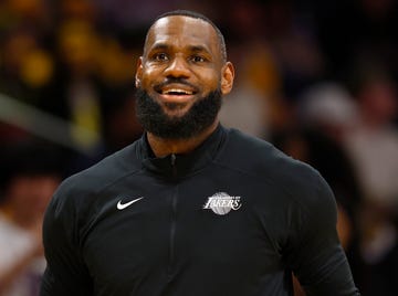 lebron james smiling, he wears a black zipup jacket with a los angeles lakers logo