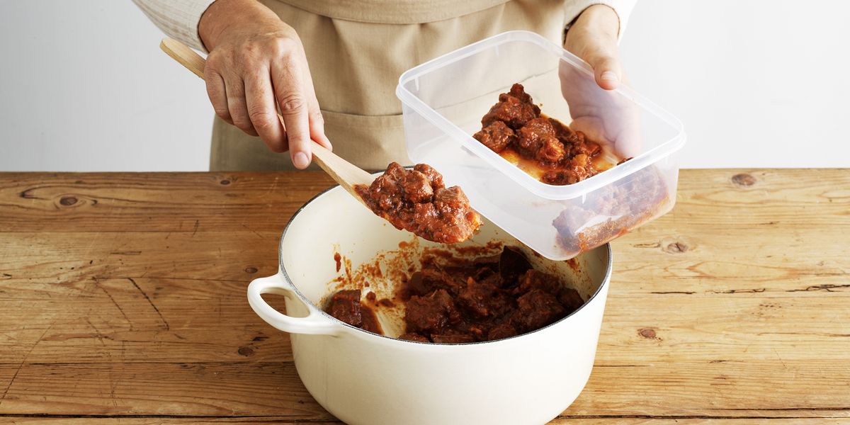 woman spooning leftover stew into a plastic container