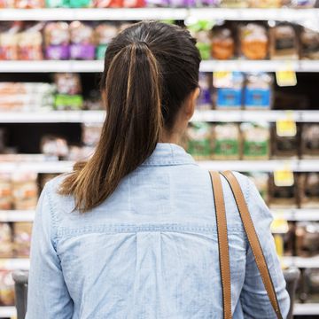 woman standing in front of bread aisle in grocery store