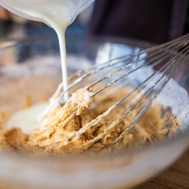 pouring almond milk into bowl of batter with whisk