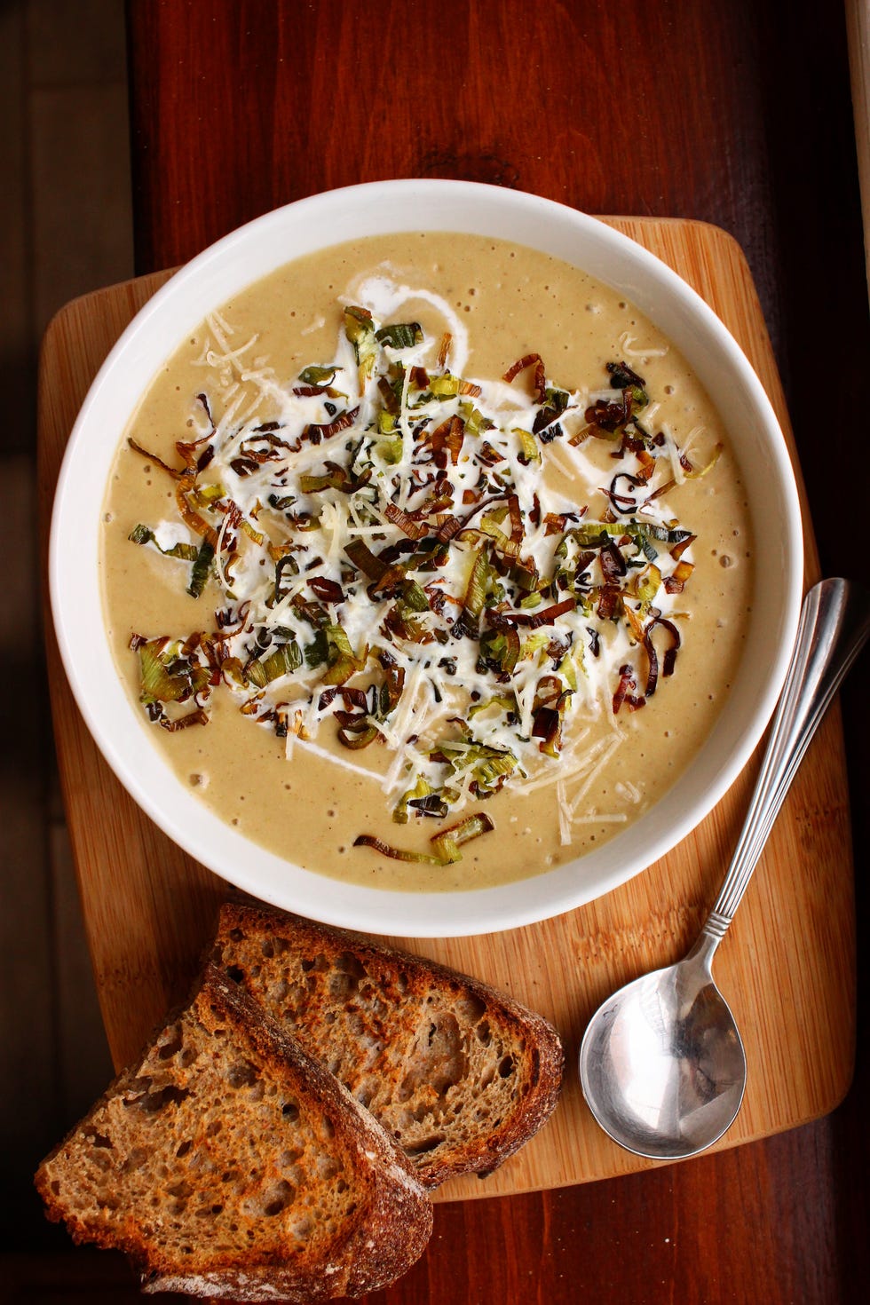 leek and potato soup in a white bowl on a dark wooden surface