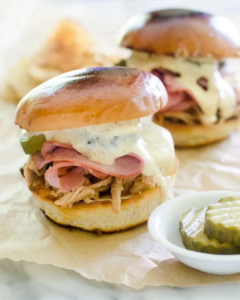 cuban inspired sandwich with mustard sauce and pickles on bun