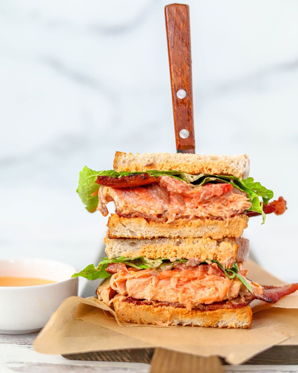 salmon blt sandwich with knife sticking in