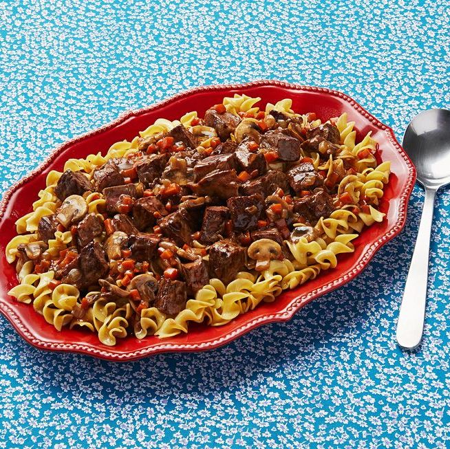 leftover steak recipes beef stroganoff over pasta on red platter with blue background