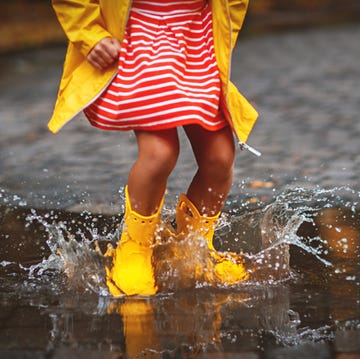 leg of child in rubber boots in puddle on autumn walk