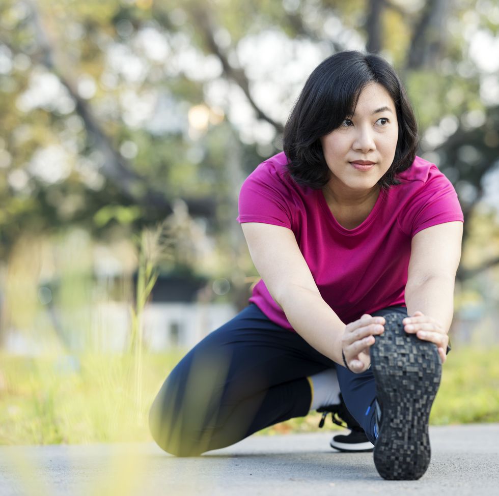 leg stretching exercise for flexibility reduce the risk of injury. a woman is doing leg stretches after running or jogging in a city park.