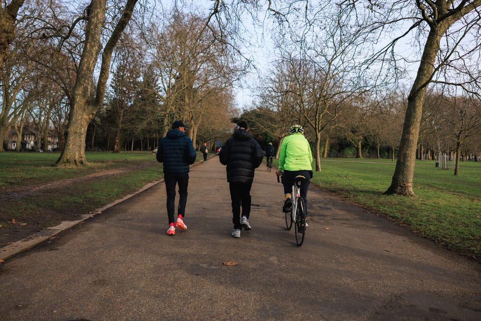 two runners and a man on a bike in a park
