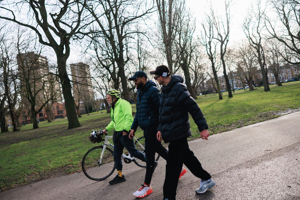 a group of individuals walking in a park with a bicycle