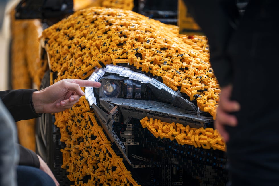 a person points at the lifesize lego technic mclaren p1's headlights with their left hand