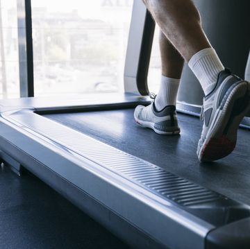 legs of male athlete running on treadmill in gym