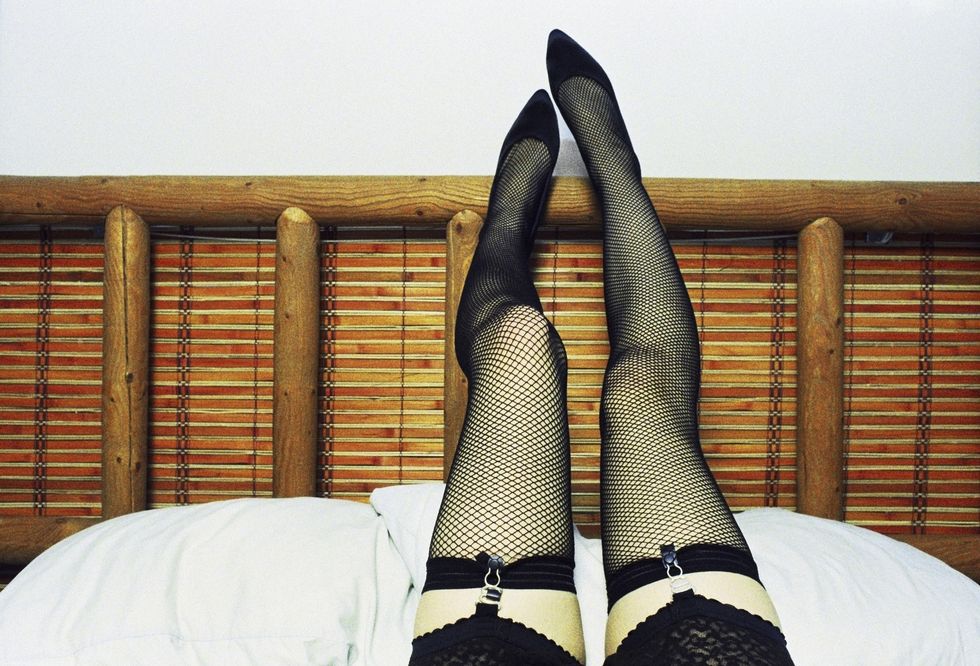Legs of woman wearing fishnet stockings on bed
