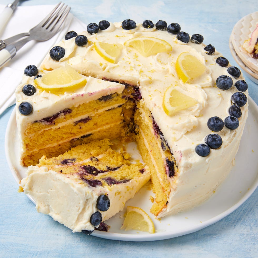 layered cake with buttercream frosting topped with lemon slices and fresh blueberries