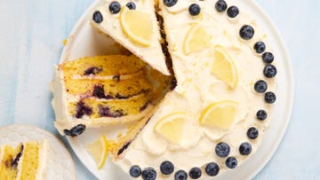 layered cake with buttercream frosting topped with lemon slices and fresh blueberries