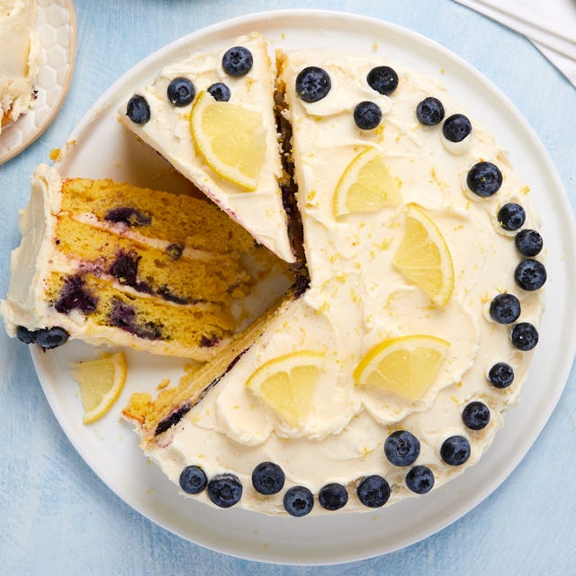 layered cake with buttercream frosting topped with lemon slices and fresh blueberries