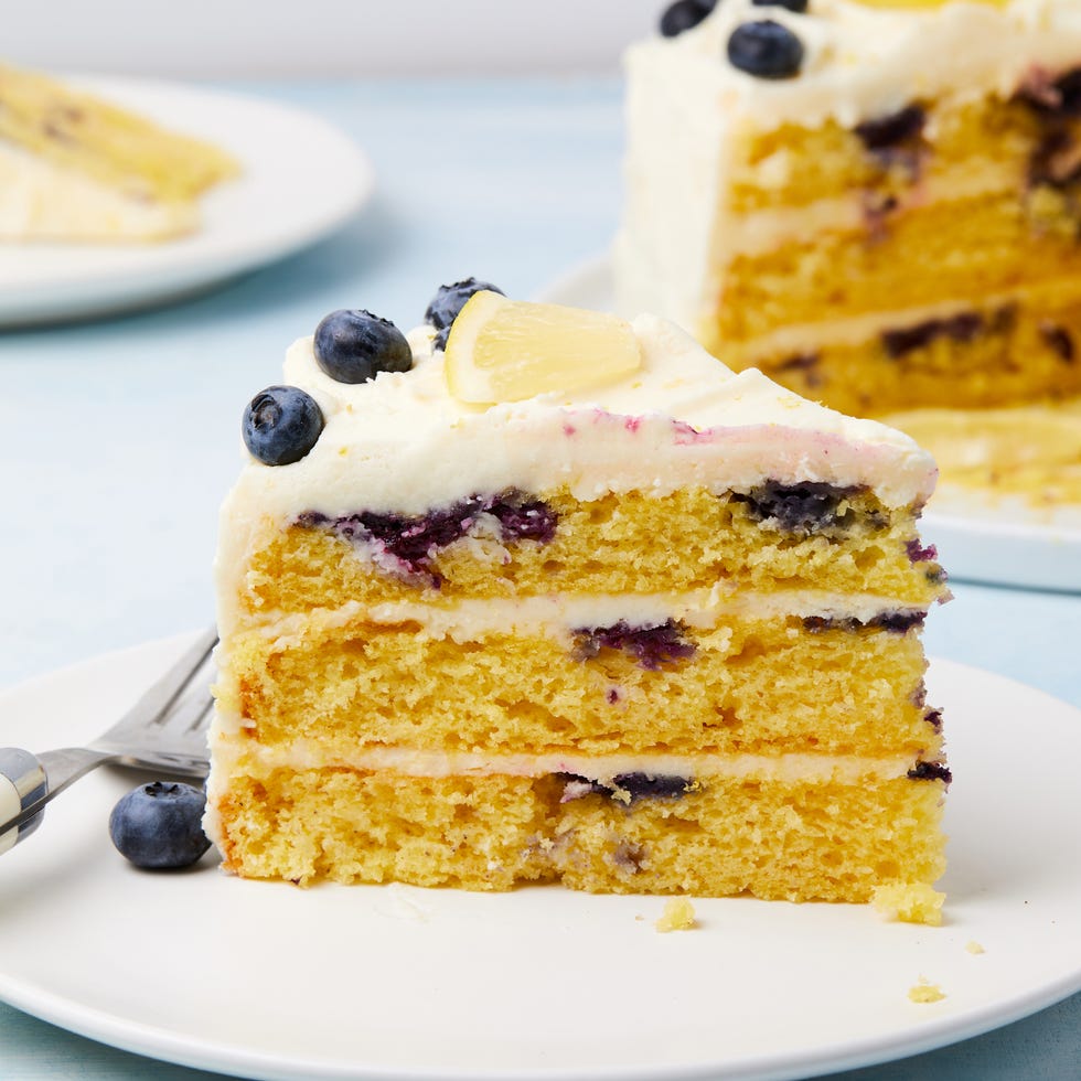 layered cake with buttercream frosting topped with lemon slices and fresh blueberries