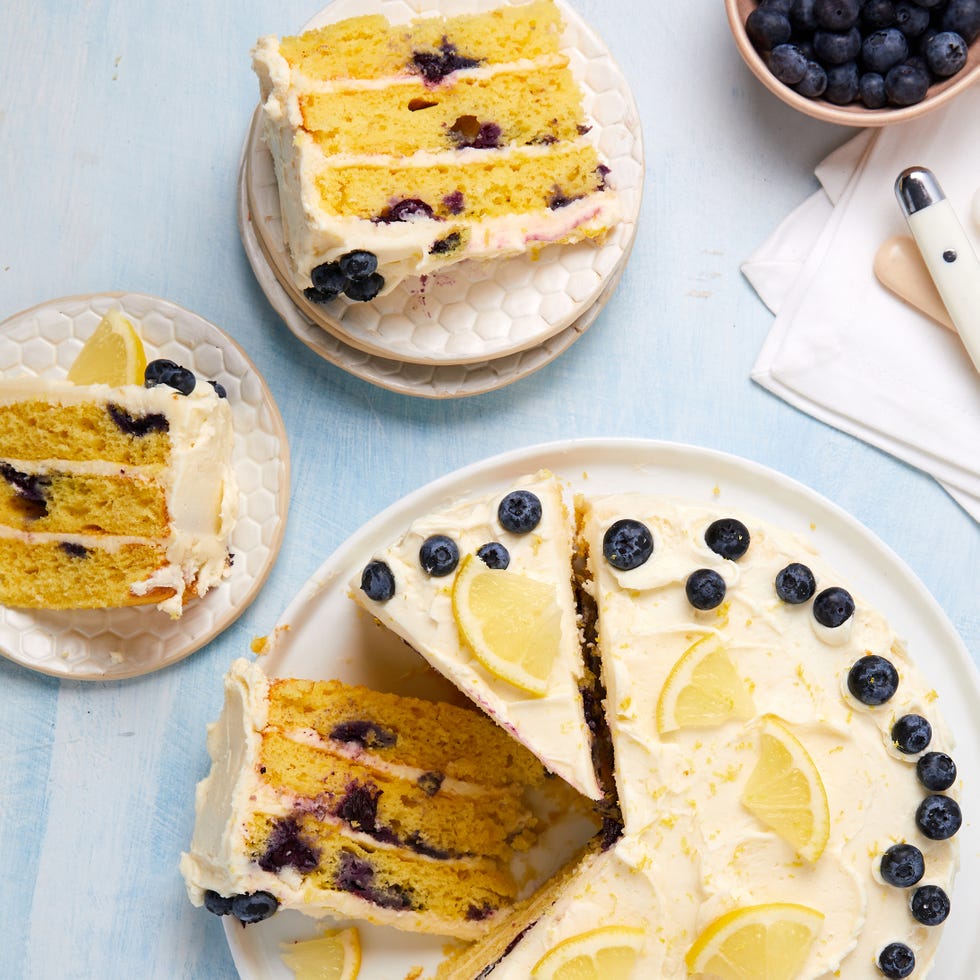 layered cake with buttercream frosting topped with lemon slices and fresh blueberries