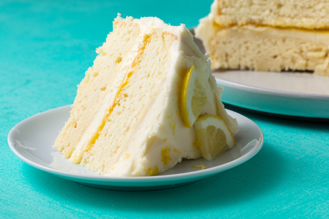 slice of easy lemon layer cake on a white plate on a teal background