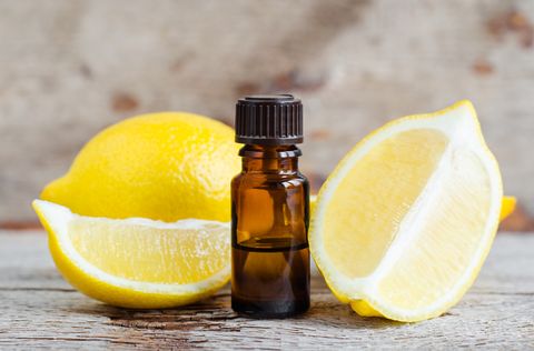 small bottle of essential lemon oil on the old wooden background aromatherapy, spa and herbal medicine ingredients copy space