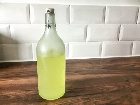 freshly chilled limoncello waiting in a glass bottle on a wooden counter in front of white metro tiles