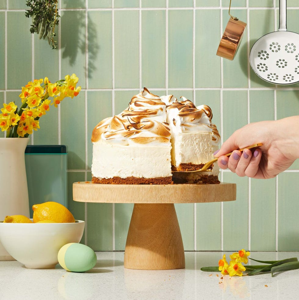 lemon meringue cheesecake on a wooden cake stand