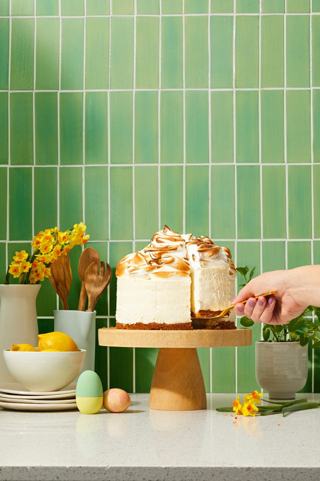 lemon meringue cheesecake on a wooden cake stand